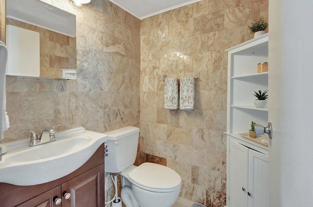 bathroom featuring vanity, crown molding, built in shelves, toilet, and tile walls