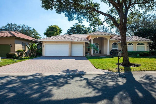 mediterranean / spanish-style house featuring a garage and a front lawn