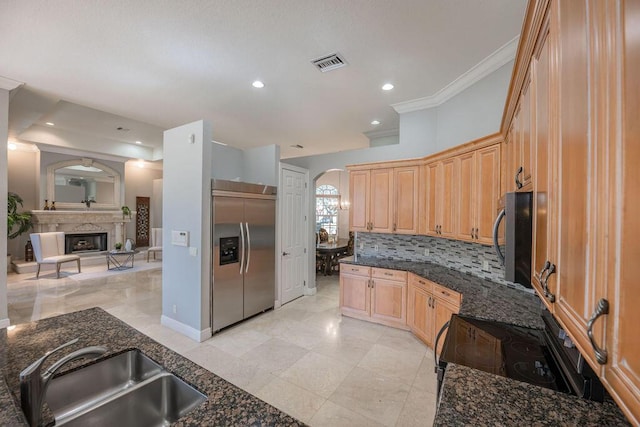 kitchen featuring built in fridge, sink, dark stone counters, and black range with electric cooktop