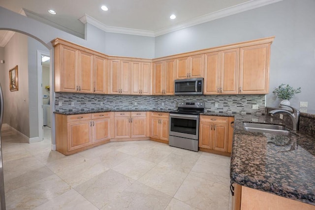 kitchen with light brown cabinets, dark stone counters, sink, ornamental molding, and stainless steel appliances