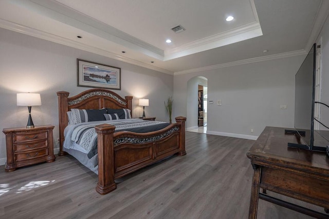 bedroom with a raised ceiling, wood-type flooring, and ornamental molding