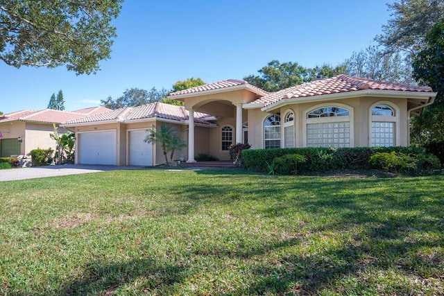 mediterranean / spanish-style home with a garage and a front lawn