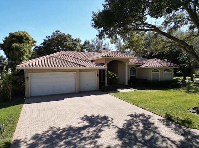 mediterranean / spanish home featuring a front lawn and a garage