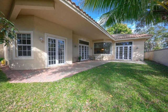 back of house with french doors, a patio area, and a lawn