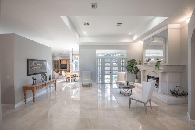 interior space featuring french doors, a raised ceiling, ornamental molding, and a premium fireplace