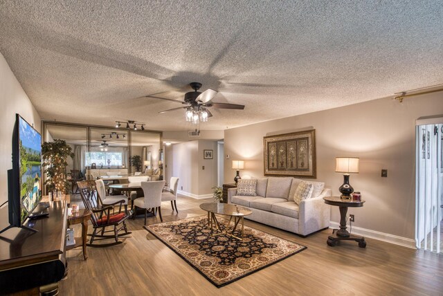 living room featuring hardwood / wood-style floors, rail lighting, a textured ceiling, and ceiling fan