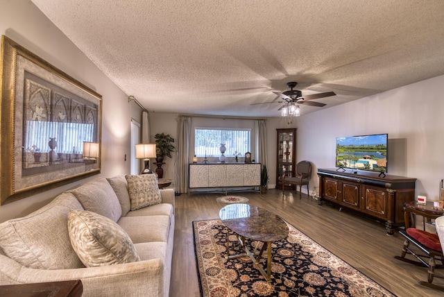 living room featuring dark hardwood / wood-style flooring, a textured ceiling, and ceiling fan