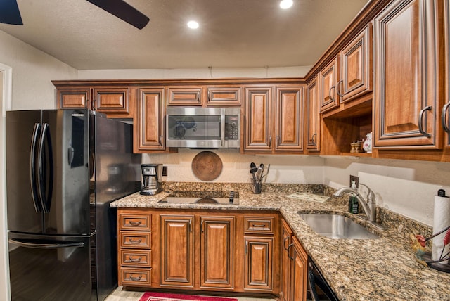 kitchen with sink, light stone counters, and black appliances