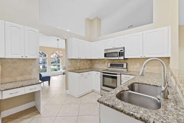 kitchen featuring light stone counters, stainless steel appliances, white cabinetry, and sink