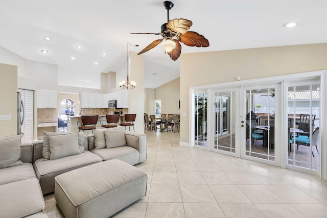 living room with light tile patterned floors, ceiling fan with notable chandelier, high vaulted ceiling, and french doors