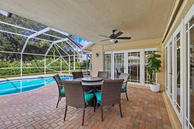 view of pool with glass enclosure, ceiling fan, a patio, and french doors