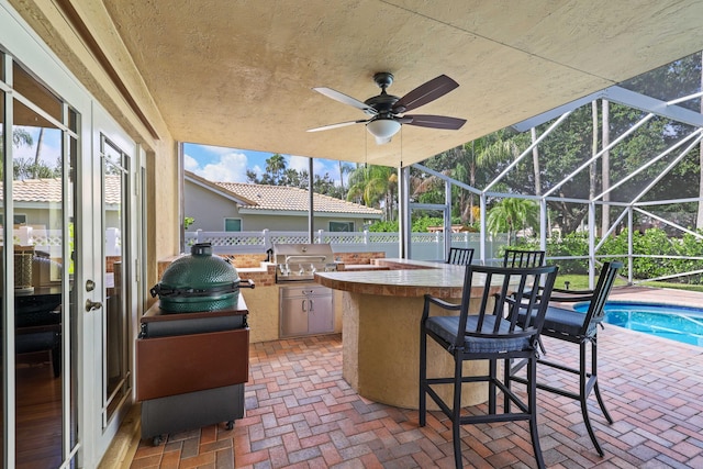 view of patio with grilling area, exterior bar, ceiling fan, a lanai, and area for grilling