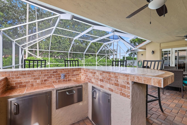 view of patio / terrace featuring a bar, ceiling fan, and a lanai