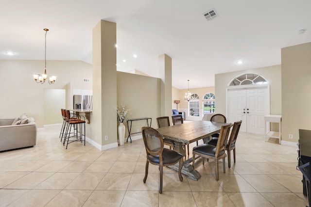 dining area with lofted ceiling, light tile patterned floors, and an inviting chandelier