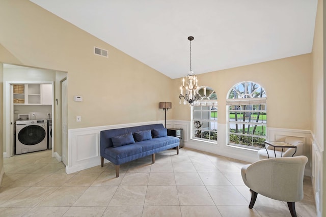 living area featuring washer and dryer, light tile patterned flooring, lofted ceiling, and a chandelier