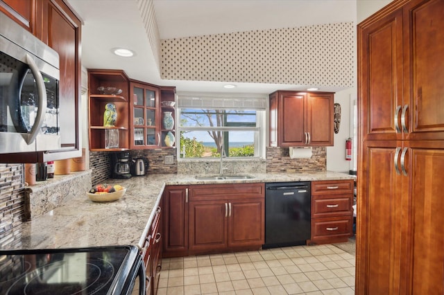 kitchen with light stone countertops, black dishwasher, sink, and decorative backsplash