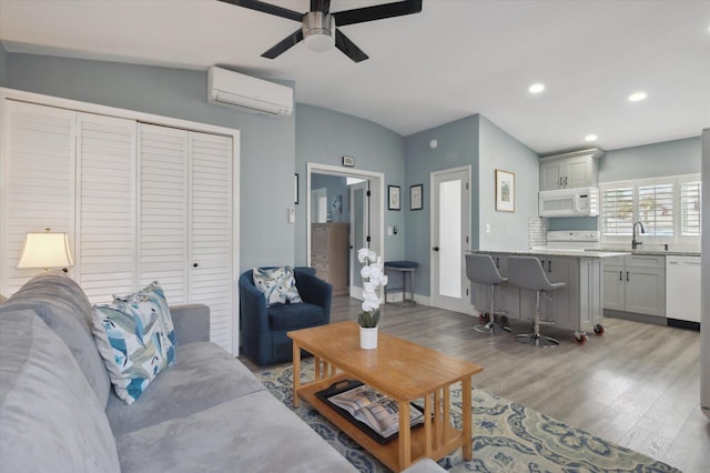 living room featuring sink, light hardwood / wood-style floors, an AC wall unit, and ceiling fan