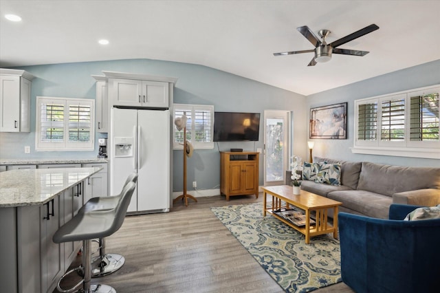 living room featuring ceiling fan, lofted ceiling, and light wood-type flooring