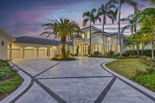 mediterranean / spanish-style home featuring a garage and a lawn