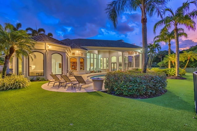 back house at dusk featuring a patio area, a yard, french doors, and a swimming pool