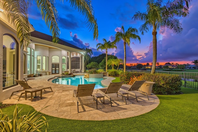 pool at dusk with a yard and a patio area