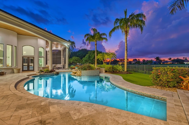 pool at dusk featuring a lawn