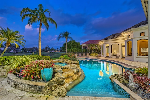 pool at dusk with a patio