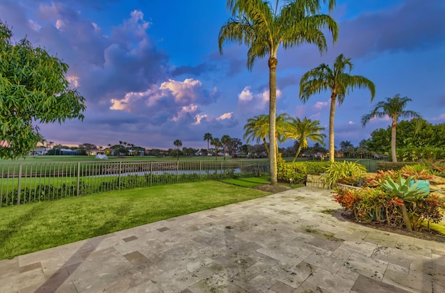 yard at dusk with a patio area and a water view