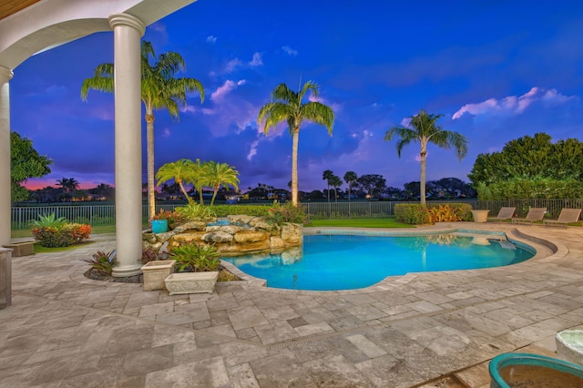 pool at dusk with a patio area