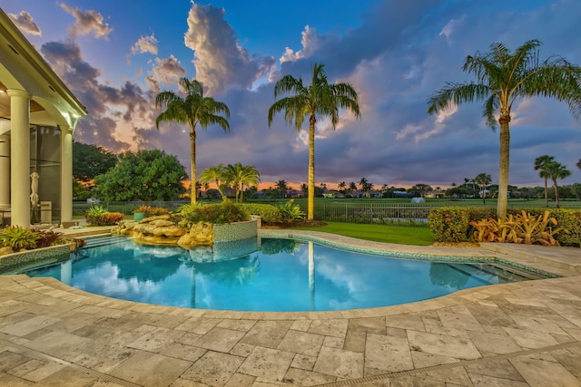 pool at dusk with a patio area