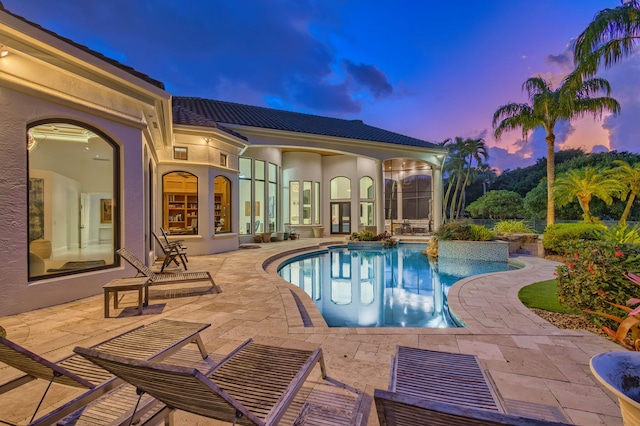 pool at dusk with a patio area