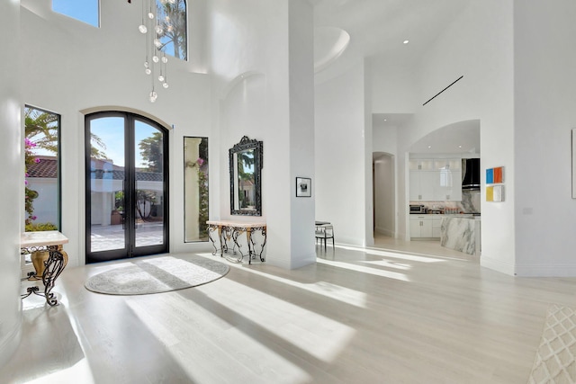 foyer featuring light wood-type flooring, a high ceiling, and french doors