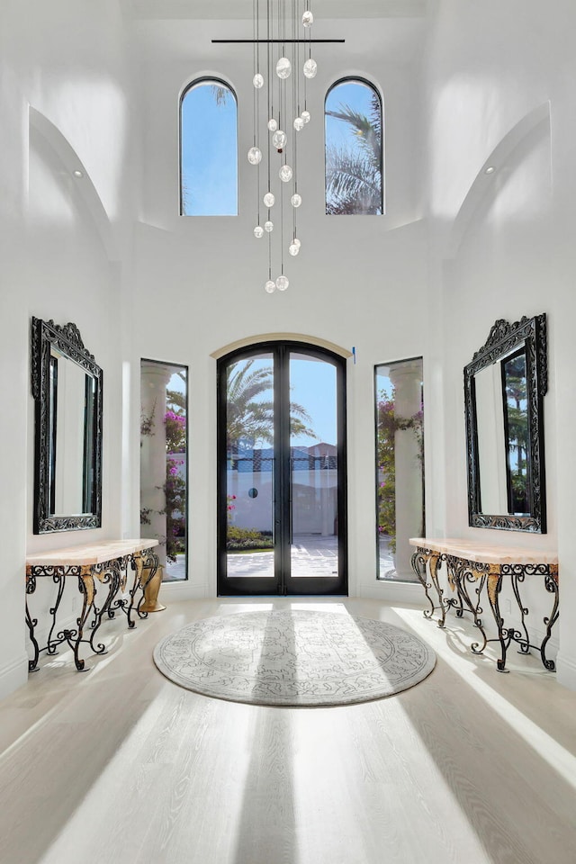 foyer entrance with french doors, a towering ceiling, and hardwood / wood-style flooring