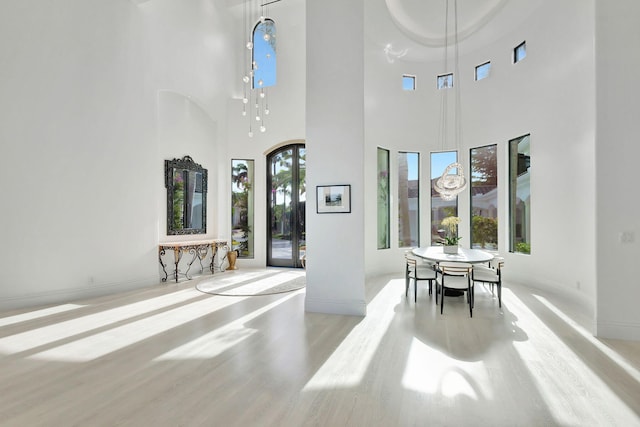 dining space with light hardwood / wood-style flooring and a high ceiling