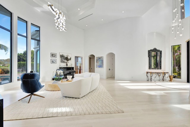 living room featuring light wood-type flooring and a towering ceiling