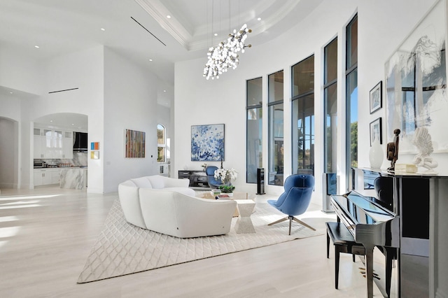 living room featuring a high ceiling, a tray ceiling, an inviting chandelier, and ornamental molding