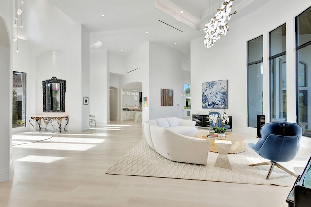 living room featuring a chandelier, a high ceiling, and light hardwood / wood-style flooring