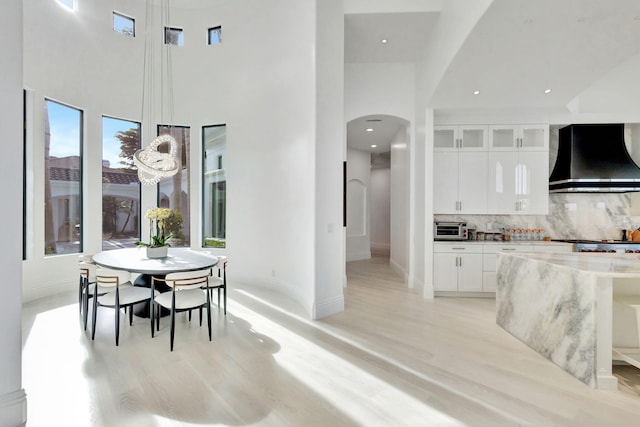 dining space with light wood-type flooring and a towering ceiling