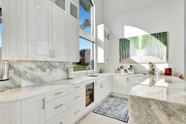 kitchen with white cabinets, light stone countertops, and beverage cooler