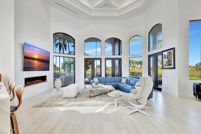 living room with french doors, a towering ceiling, plenty of natural light, and ornamental molding