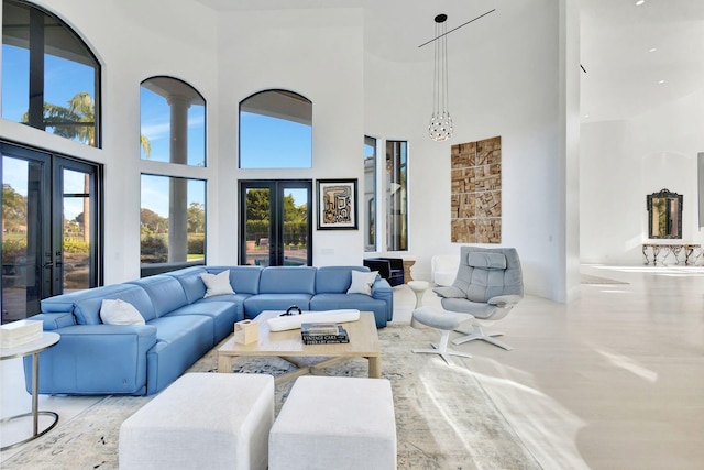 living room with a healthy amount of sunlight, a towering ceiling, and french doors