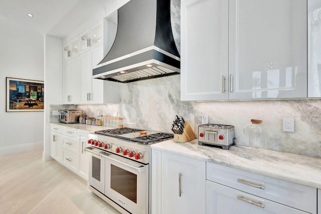 kitchen with white cabinetry, range with two ovens, and custom range hood