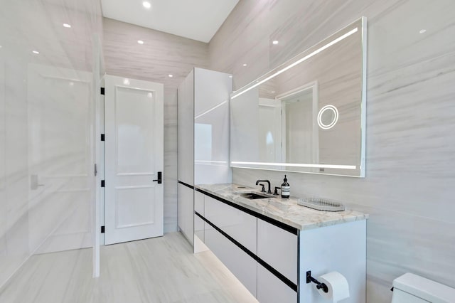 bathroom featuring vanity, toilet, and tile walls