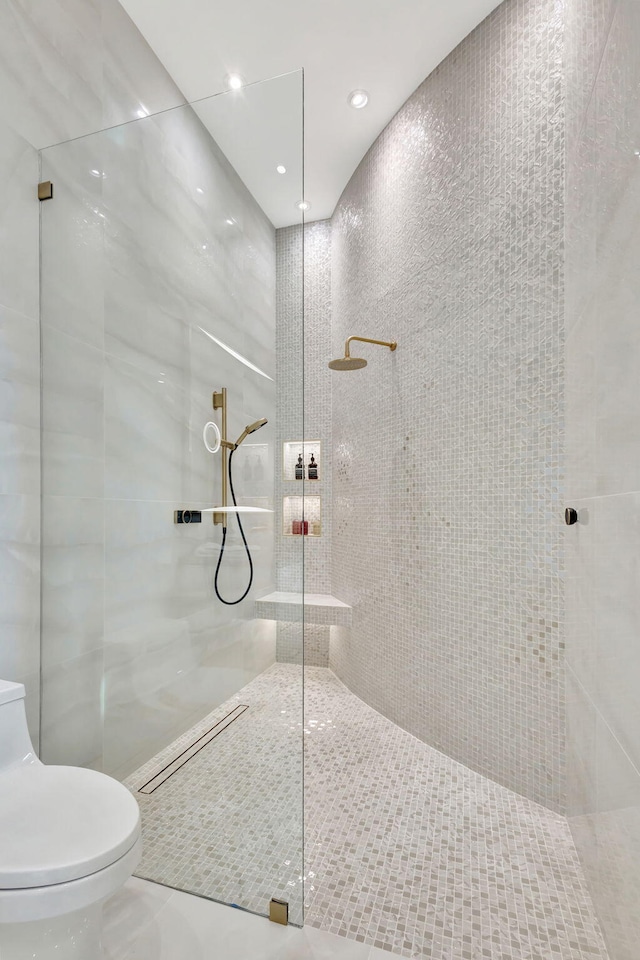 bathroom with a tile shower, tile patterned floors, and toilet