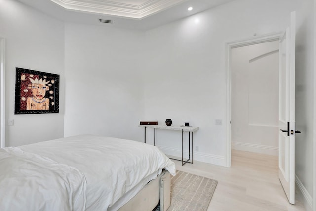 bedroom with a tray ceiling, crown molding, and light hardwood / wood-style floors