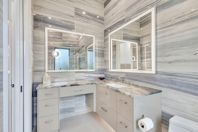 bathroom featuring tile patterned flooring, vanity, tile walls, and toilet