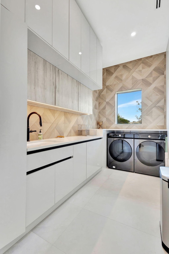 laundry area featuring cabinets, separate washer and dryer, sink, and light tile patterned floors