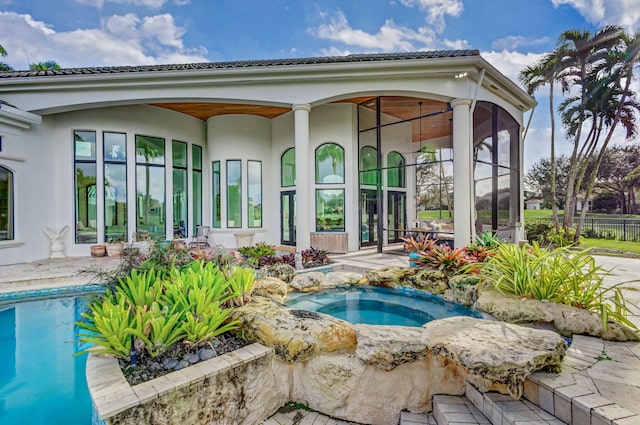 rear view of property with a swimming pool with hot tub