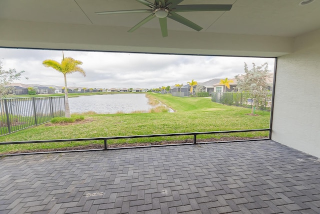 unfurnished sunroom featuring ceiling fan and a water view