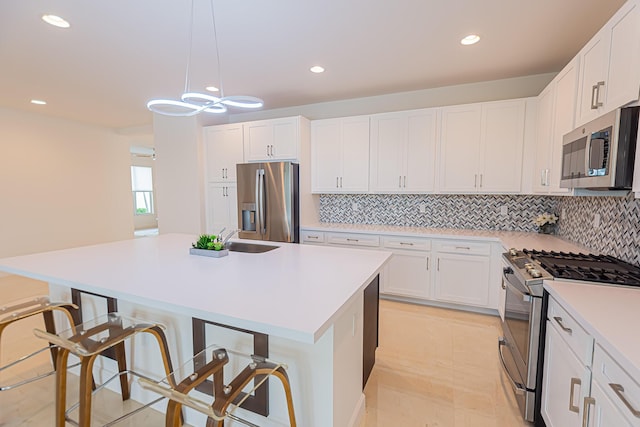 kitchen with a kitchen island, white cabinetry, appliances with stainless steel finishes, and pendant lighting